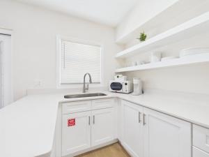 a white kitchen with a sink and a microwave at Shell & Shore in Cocoa Beach