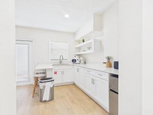 a white kitchen with white cabinets and a trash can at Shell & Shore in Cocoa Beach