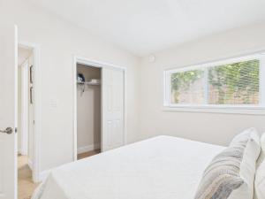 a white bedroom with a bed and a window at Shell & Shore in Cocoa Beach