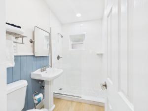 a white bathroom with a shower and a sink at Shell & Shore in Cocoa Beach