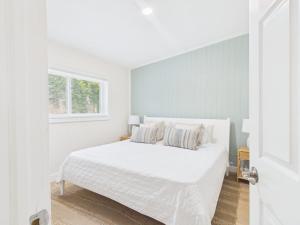 a white bedroom with a white bed and a window at Shell & Shore in Cocoa Beach