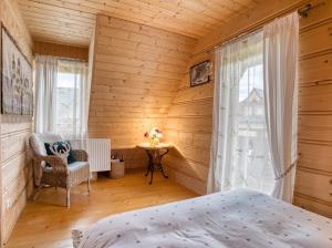 a bedroom with a bed and a chair and a table at Domek Regionalny Bąkowo Chatka in Witów