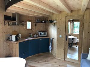 a kitchen in a wooden cabin with a microwave and a table at Le P’tiot Utau in Chapelle-Voland