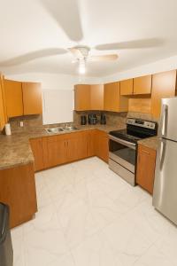 a kitchen with wooden cabinets and a white tile floor at Fauna Beach in Gold Coast Heliport