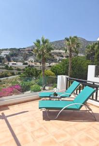 a pair of blue lounge chairs on a patio with palm trees at Sun Set at Coral Bay in Peyia