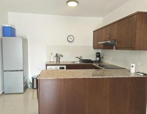a kitchen with wooden cabinets and a white refrigerator at Sun Set at Coral Bay in Peyia