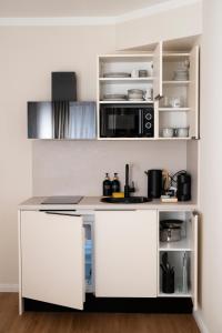 a white kitchen with a counter and a microwave at Miki Stays - 200m zum Prater in Vienna