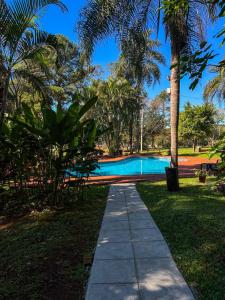 a path leading to a swimming pool in a park at Hotel & Restaurant Las Brisas in Puerto Esperanza
