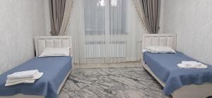 two beds in a white room with towels on them at AiDan BB in Kazarman