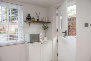 a kitchen with a microwave on a counter next to a window at The Annexe in Cobham +2 photos