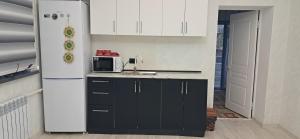 a kitchen with black cabinets and a white refrigerator at AiDan BB in Kazarman