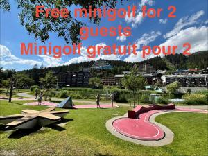 a playground in a park with people walking on the grass at Charmant appartement hyper central, idéal pour couple ou petite famille, parking couvert in Crans-Montana