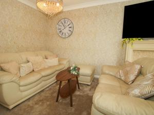 a living room with couches and a clock on the wall at 18 Hengrave Meadow in Telford