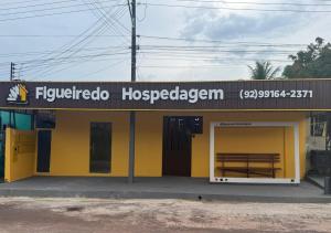 a yellow building with a wooden bench in front of it at Figueiredo Hosp 2 in Presidente Figueiredo