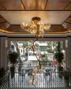 a chandelier hanging from a balcony with tables and chairs at Selah Hanoi Hotel in Hanoi