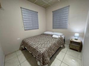a small bedroom with a bed and two windows at Casa Colibrí Volcán in Volcán
