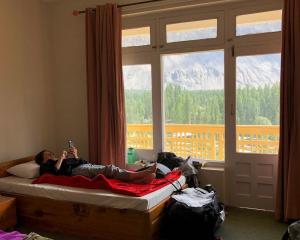 a woman laying on a bed in a room with a window at Hotel Mashabrum Skardu Free Breakfast Mountain View Family Rooms & Free WiFi in Skardu +87 photos