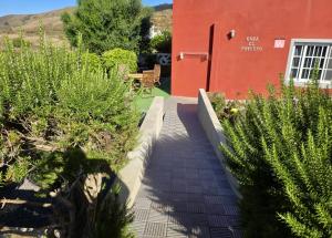 a walkway leading to a red building with plants at Casa El Potrero in Mocanal