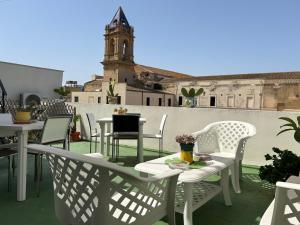 a patio with white tables and chairs and a clock tower at B&B Ramura in Mazara del Vallo