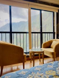 a room with two chairs and a table and a balcony at Snowra heights in Abbottabad