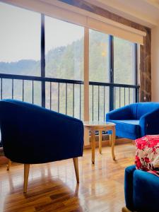 a living room with two blue chairs and a table at Snowra heights in Abbottabad +2 photos