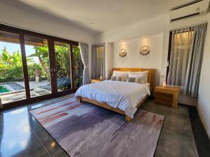 a bedroom with a bed and a large window at Villa Dew Canggu in Kerobokan