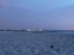 a sandy beach with a pier in the distance at Ferienwohnung _ Kartenraum _ Objek in Warnemünde