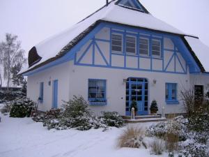 a white house with blue trim in the snow at Ferienhaus Diekelmann _ Objekt 258 in Diedrichshagen