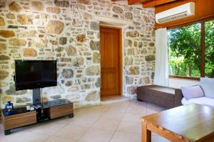 a living room with a tv and a stone wall at Villa Limon by Important Group Travel in Bitez