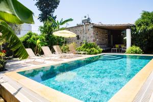 a pool with chairs and an umbrella next to a house at Villa Limon by Important Group Travel in Bitez
