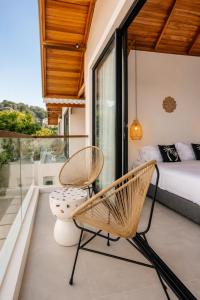 a bedroom with a bed and two chairs on a balcony at FinnKai Villas in Sengkol