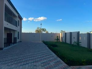 a brick walkway next to a building with a fence at Ravens nests lodge in Livingstone