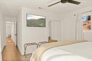 a white bedroom with a bed and a ceiling fan at Modern Hideaway in Big Bear in Big Bear City