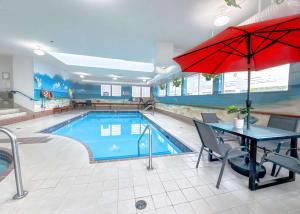 a pool with a table and a red umbrella at Coast Abbotsford Hotel & Suites in Abbotsford
