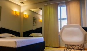 a bedroom with a bed and a white chair and a mirror at Hotel Css in Ituzaingó