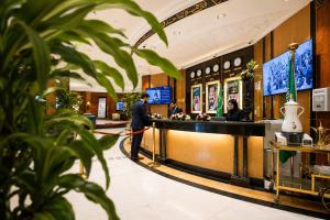 a man standing at a counter in a hotel lobby at Golden Tulip Al Shakreen in Medina