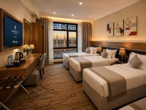 a hotel room with two beds and a television at Golden Tulip Al Shakreen in Medina +79 photos