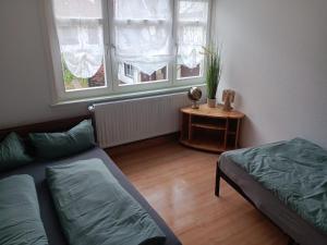 a room with two beds and a table and two windows at Horstis Fewo Apartment Reni in Frankenhain