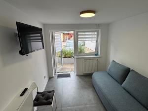 a living room with a blue couch and a television at Piankowe mini-apart in Rewal +9 photos