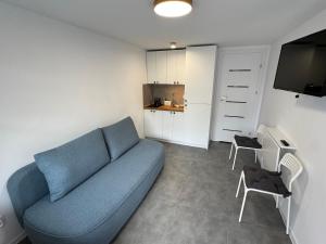 a living room with a blue couch and a kitchen at Piankowe mini-apart in Rewal