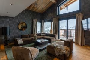a living room with a couch and chairs and windows at Les Chalets de l'Observatoire in Megève