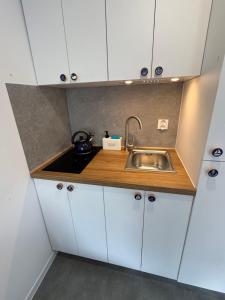 a kitchen with white cabinets and a sink at Piankowe mini-apart in Rewal