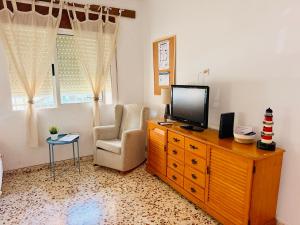 a living room with a television on a dresser and a chair at Cala de Los Lobos in Puerto de Mazarrón