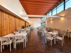 a restaurant with white tables and chairs and windows at Hotel SunClub CalaVinya in Salou