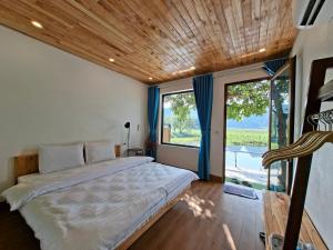 a bedroom with a large bed and a large window at Vivian riverside cottage - Ninh Bình in Nguyên Ngoại