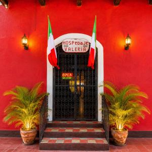 a red building with a black door and two flags at Hotel Valeria in Granada