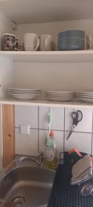 a kitchen sink with plates and dishes on a shelf at Mysan in Glommersträsk