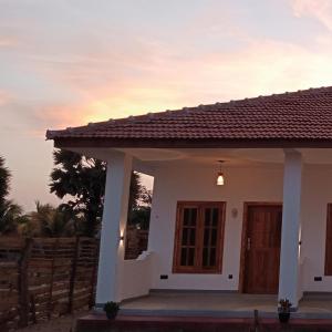 a small white house with a sunset in the background at Hungry Wave in Arugam Bay