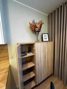 a wooden book shelf with a vase of flowers on it at Cozy corner89, private parking in Valmiera