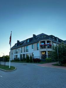 a large white building with a flag on a street at Cozy corner89, private parking in Valmiera